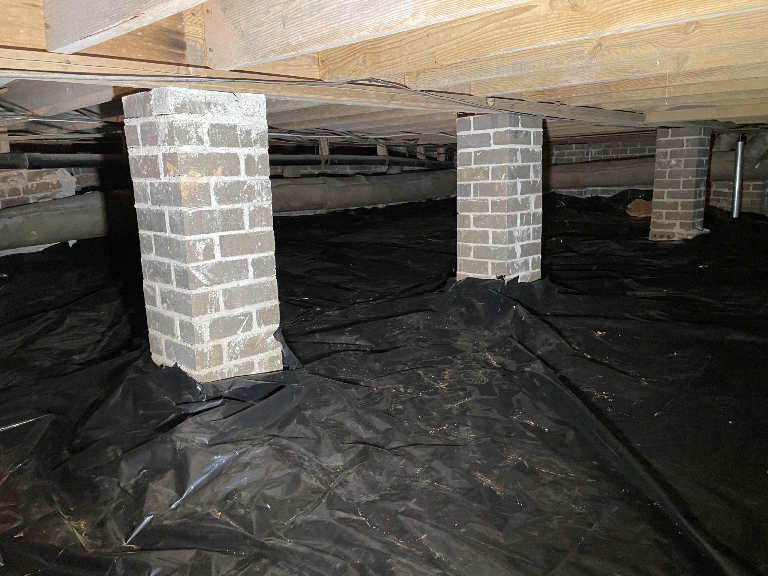Brick piers and wood beams in the crawlspace of an older Upstate SC home